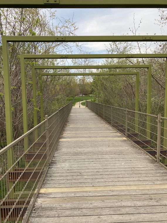 A wooden boardwalk with metal railings leading through Evans Parkway Park